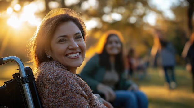 A smiling woman turning toward the camera from her wheelchair outdoors